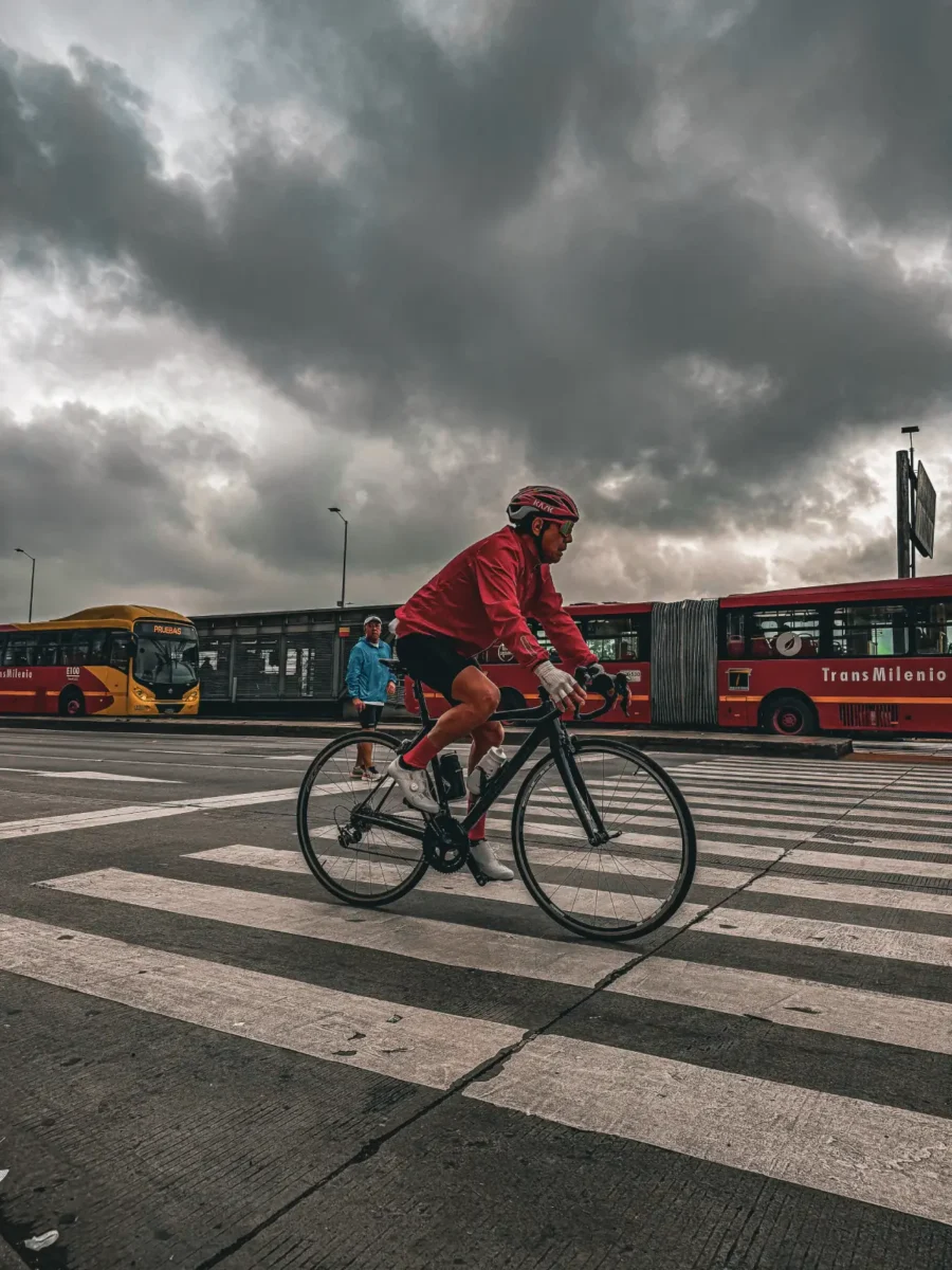 Hombre en bicicleta en la ciclovía de Bogotá, detrás de él se observa TransMilenio