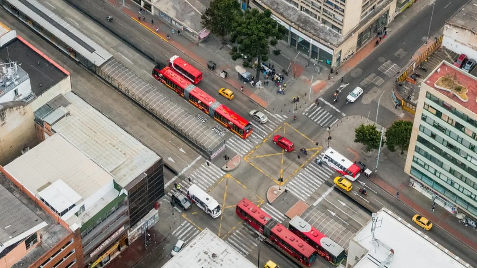 Foto de Bogotá: desde la altura se ve una calle por donde transitan vehículos particulares, buses de TransMilenio y más.