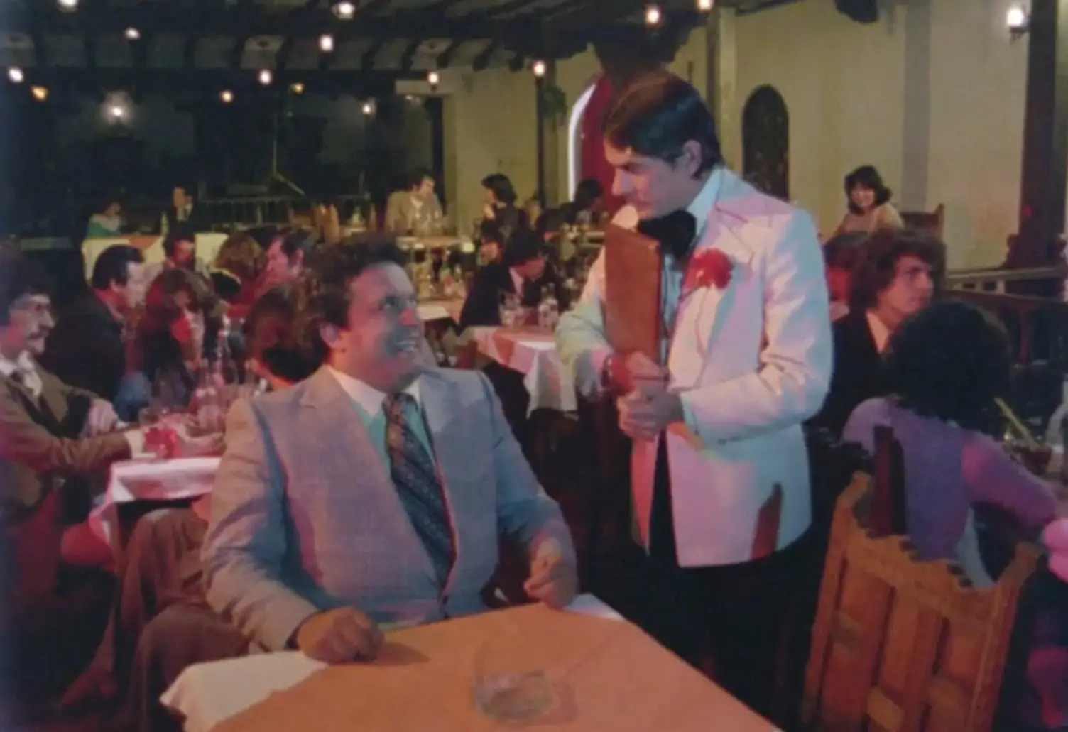 José conversando con un mesero en un bar.