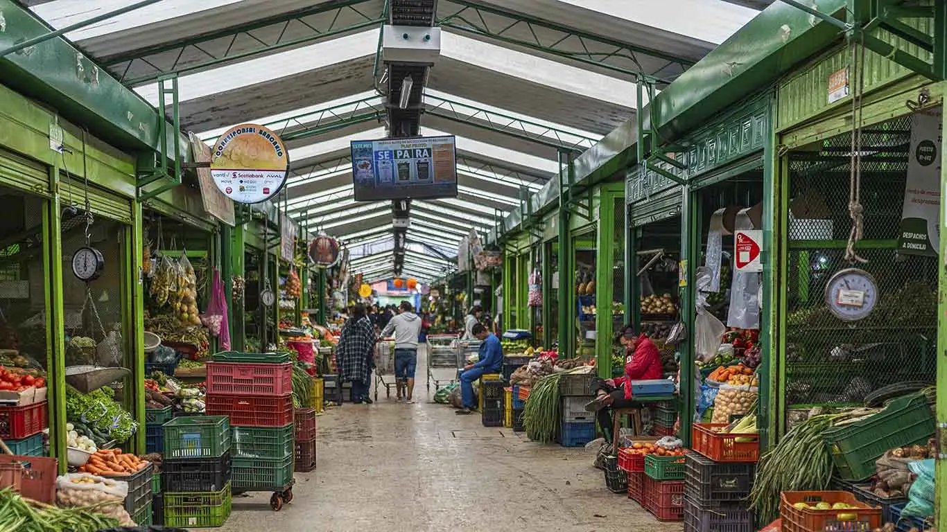Pasillo de la Plaza de Mercado de Paloquemao con comerciantes en cada lado.