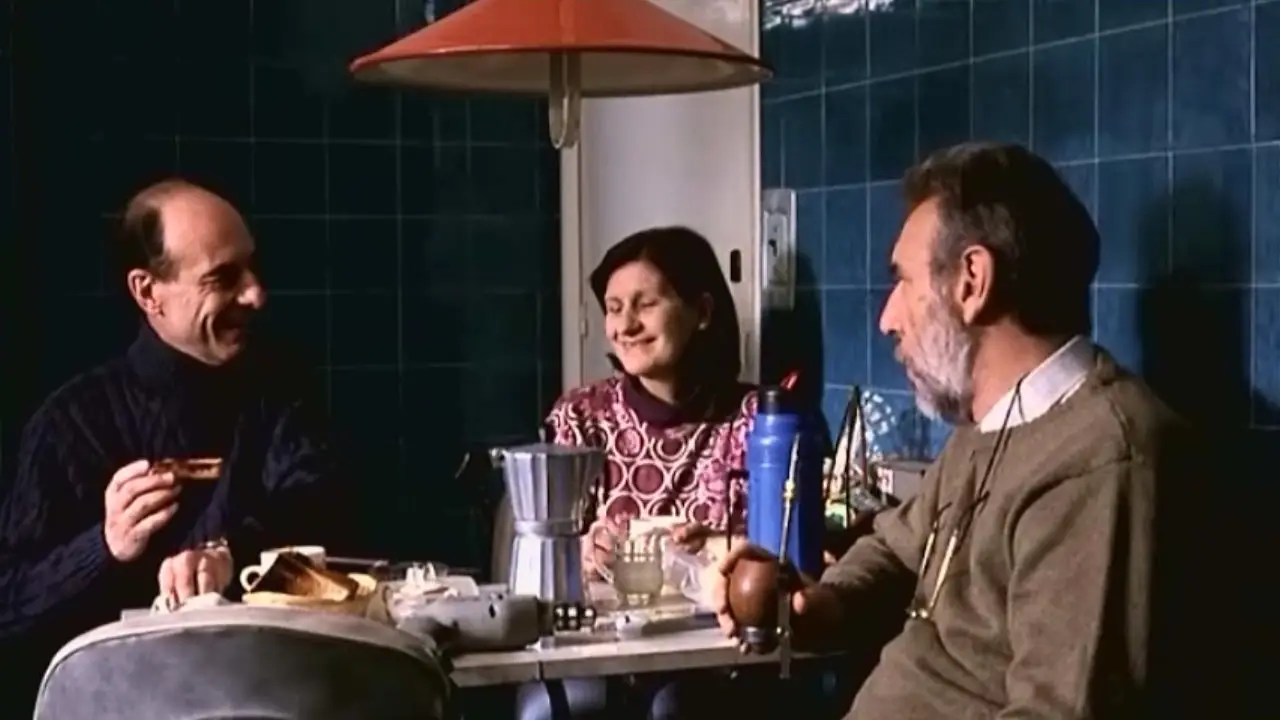 Imagen de la película Whisky, se ve tres personas compartiendo en una mesa