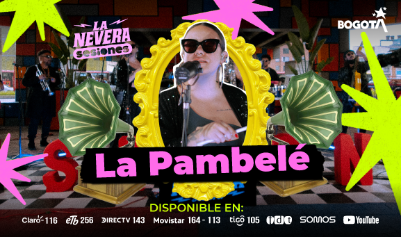 Cantante de La Pambelé con gafas oscuras canta frente a un micrófono durante presentación en La Nevera Sesiones en Bogotá, con banda e instrumentos al fondo