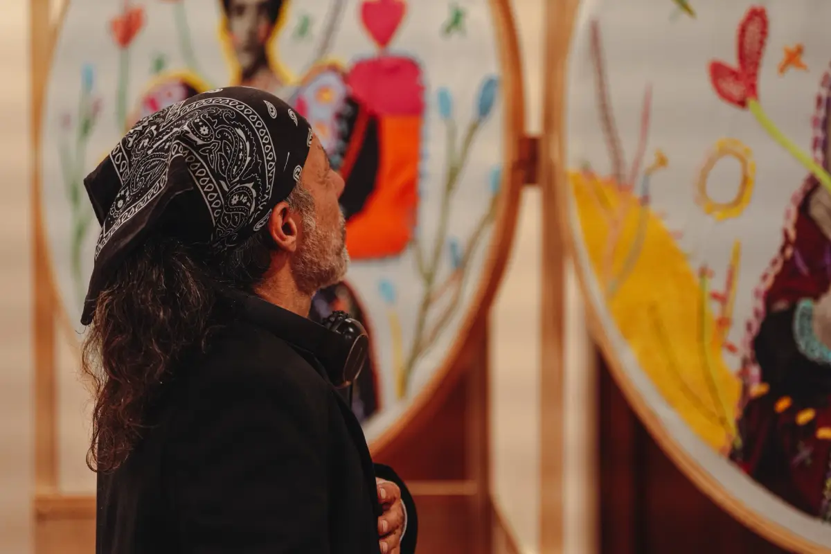 Un hombre visita la exposición Artífices y Pensadoras y observa uno de los bordados