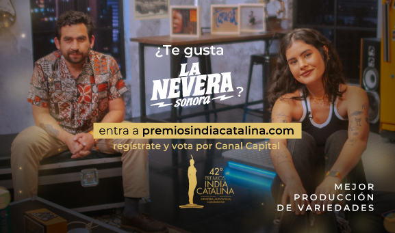 Hombre y mujer jóvenes sentados en estudio musical con instrumentos y decoración, posan frente a cámara en escena del programa La Nevera Sonora de Canal Capital