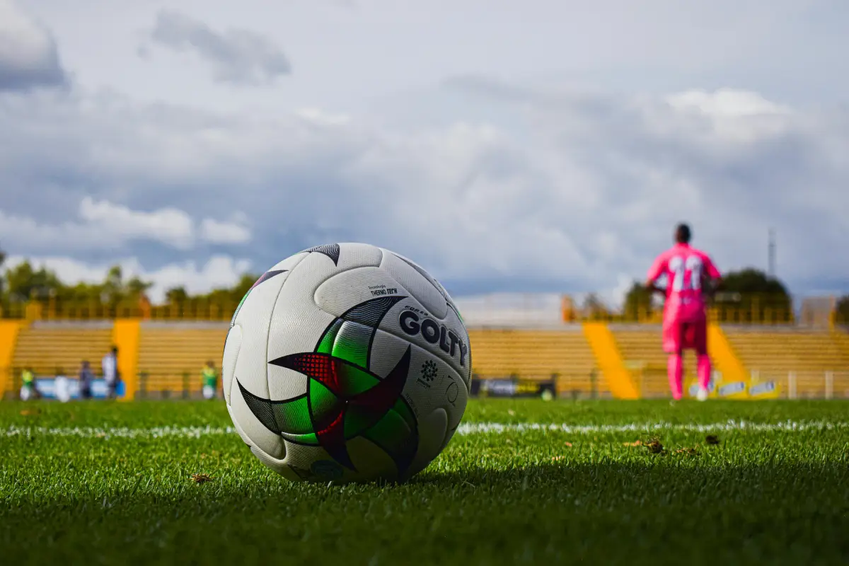 Personas juegan futbol en una cancha y se ve un balón