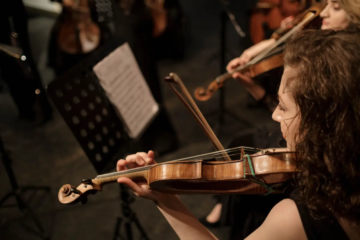 Una violinista hábil en una orquesta tocando con elegancia y pasión.