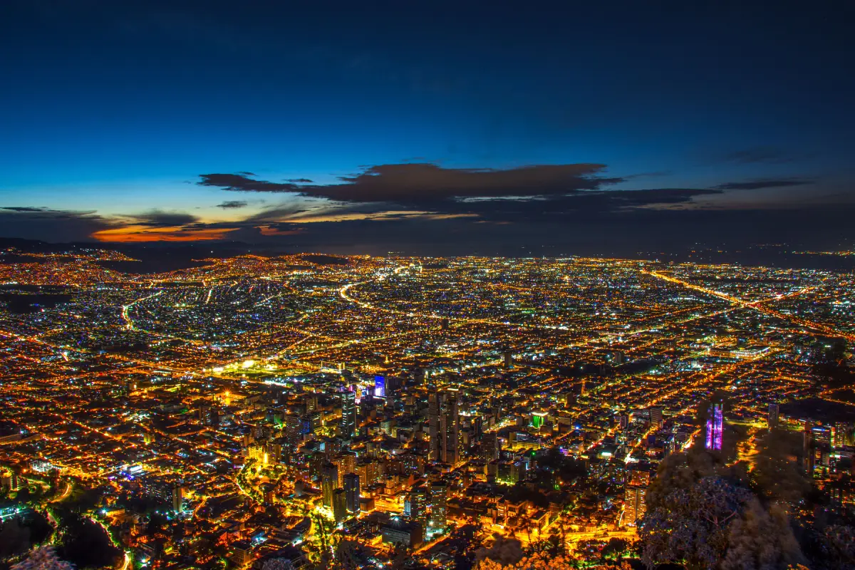 Una impresionante vista aérea de las luces de la ciudad de Bogotá bajo un cielo crepuscular.